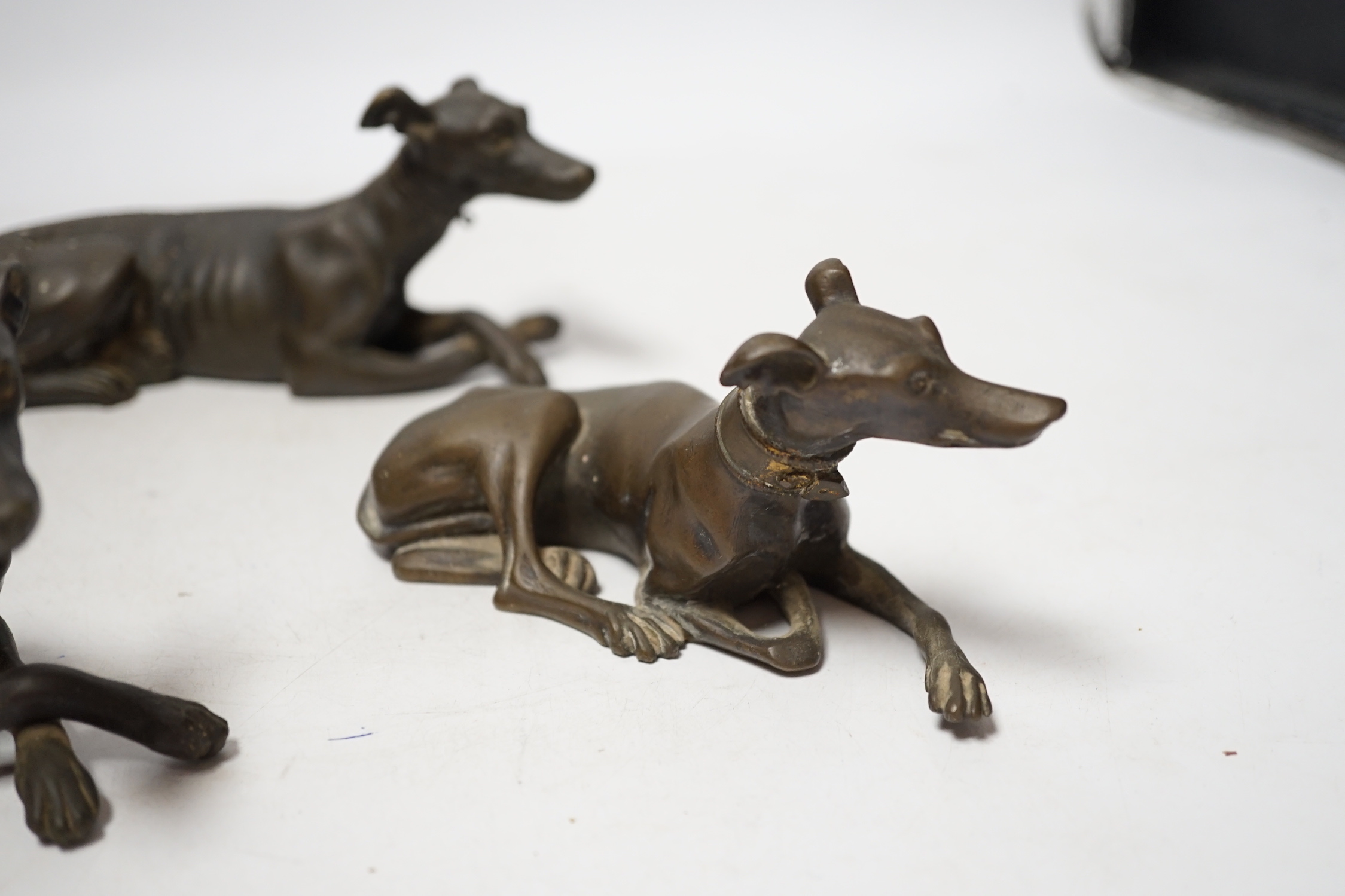 Three late 19th century bronze models of recumbent greyhounds, 17cm